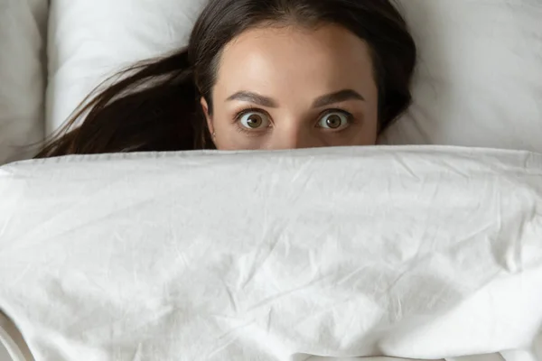 Tutup tampilan atas wanita muda lucu mengintip dari selimut — Stok Foto