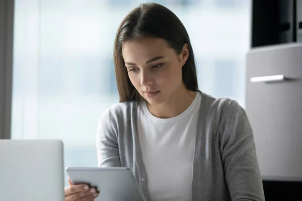 Joven empresaria seria mirando la pantalla de la tableta del ordenador en la oficina —  Fotos de Stock