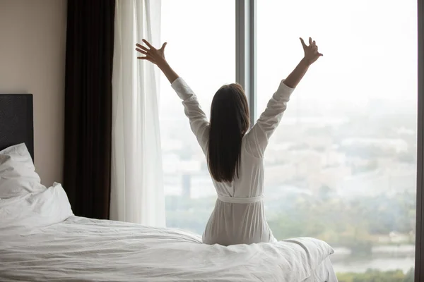 Vista posteriore giovane donna che indossa accappatoio stretching dopo il risveglio — Foto Stock