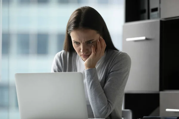 Несчастная молодая деловая женщина смотрит на экран ноутбука, читает новости — стоковое фото
