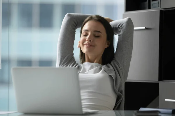 Sorrindo pacífica jovem empresária inclinando-se para trás em confortável cadeira de escritório — Fotografia de Stock