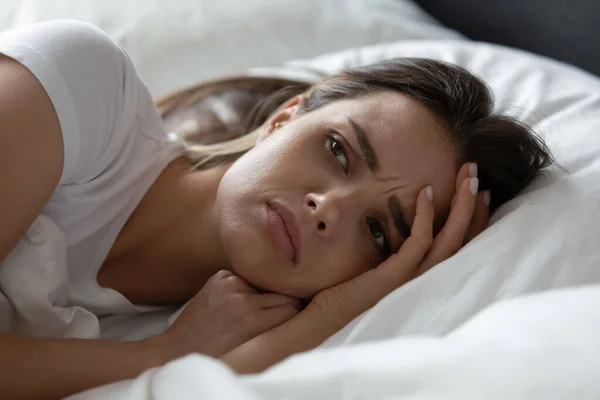 Acercamiento mujer joven estresada acostada en la cama sola — Foto de Stock