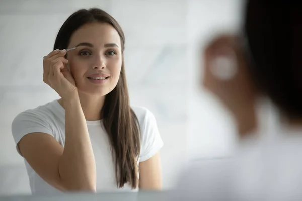 Großaufnahme Kopfschuss lächelnde Frau zupft Augenbrauen mit Pinzette — Stockfoto