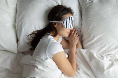 Maskeli, huzurlu, genç bir kadın yan yana uyuyor.