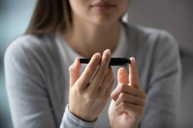 Glikoz seviyesini ölçmek için tükenmez kalem kullanan genç bir kadını kapatın.