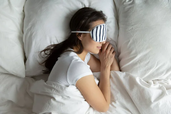 Top tampilan wanita muda yang damai mengenakan masker tidur di samping — Stok Foto