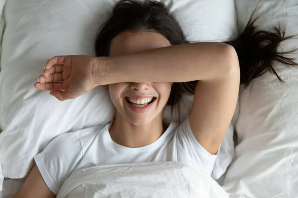 웃는 여자가 침대에서 손으로 눈을 가리고 있는 맨 위 사진 — 스톡 사진