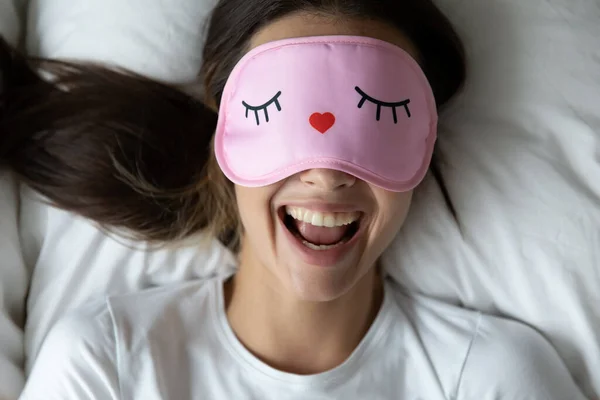 Tope vista de cerca la mujer llena de alegría que usa la máscara de dormir divertido —  Fotos de Stock