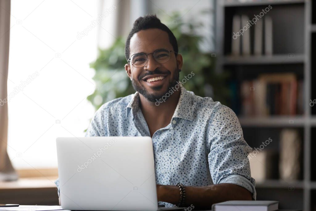 Head shot portrait smiling African American businessman with laptop