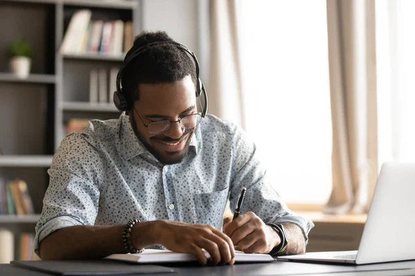 Smiling motivated African American student listening to lecture, writing notes — Stock Photo, Image