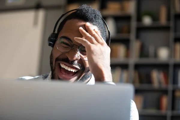 Rire homme afro-américain portant des écouteurs regardant l'écran d'ordinateur portable — Photo