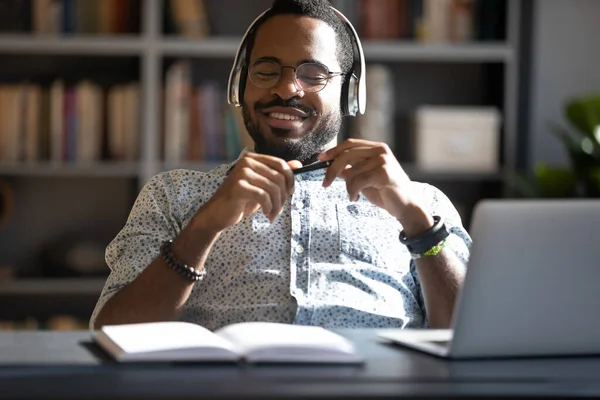 Uomo d'affari afroamericano soddisfatto che indossa cuffie godendo della musica — Foto Stock