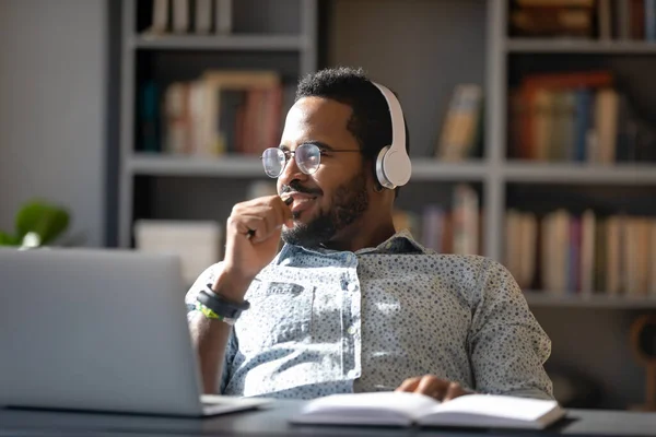 Sonhador sorrindo afro-americano homem usando fones de ouvido olhando para o lado — Fotografia de Stock