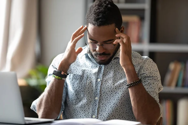 Gestresster Afroamerikaner mit Brille berührt Schläfen — Stockfoto