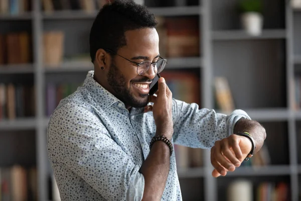 Leende afroamerikan kollar tiden medan han ringer. — Stockfoto