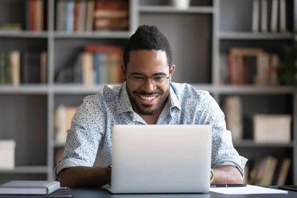 Laughing African American man using laptop, looking at screen