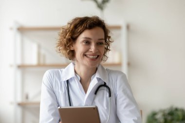 Gülümseyen kadın doktor elinde dijital tablet, hastanede çalışıyor.