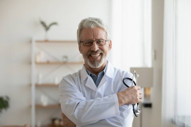 Kamera karşısında gülümseyen olgun bir doktor portresi.