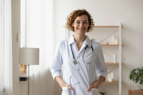 Portrait smiling young woman wearing uniform, doctor standing in office — Stock Photo, Image