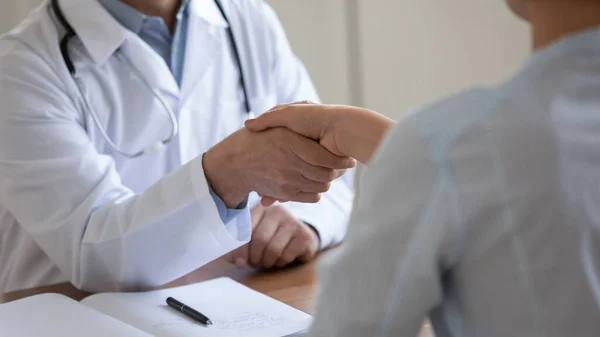 Закройте зрелого врача, пожимающего руку пациентке на встрече — стоковое фото