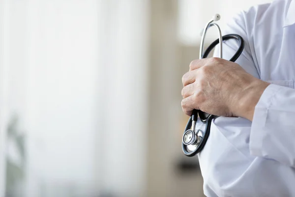 Крупним планом зрілий лікар в білій формі тримає стетоскоп — стокове фото