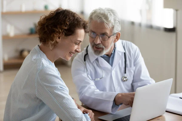 Arkadaş canlısı olgun doktor toplantıda gülen hastayla konuşuyor. — Stok fotoğraf