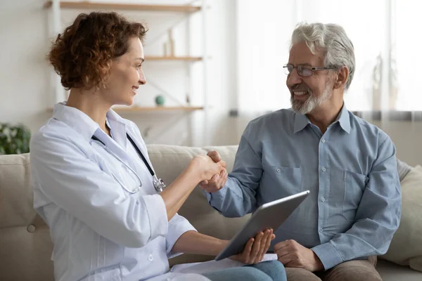 Smiling mature patient shaking doctor nurse hand at meeting — Stock Photo, Image