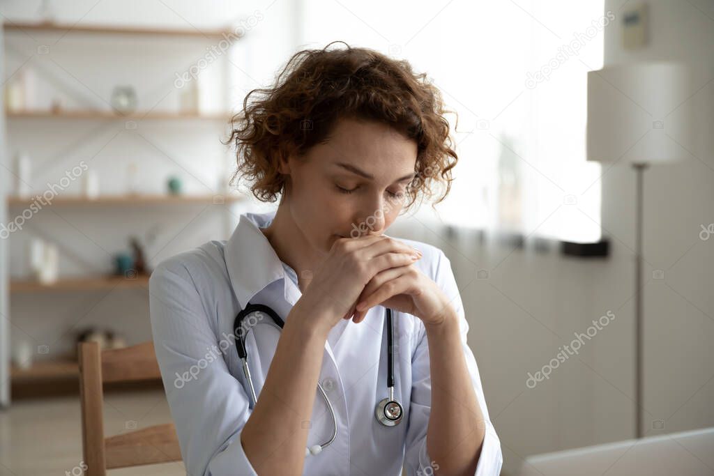 Close up thoughtful woman doctor sitting at work desk