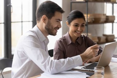 Çevrimiçi projede çalışan gülümseyen genç karışık ırk yöneticileri.