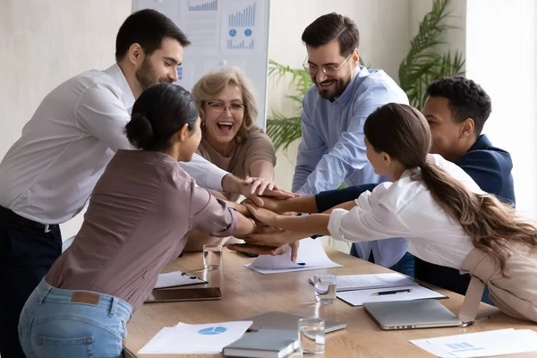 Щаслива лідерка середнього віку, яка об'єднує руки з молодими колегами . — стокове фото