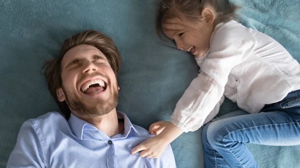 Счастливая маленькая девочка щекочет смеющийся молодой отец. — стоковое фото