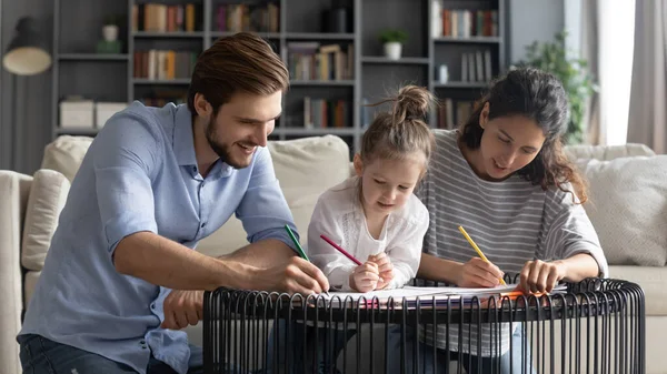 Joyeux jeune famille avec enfant d'âge préscolaire appréciant colorier des photos à l'intérieur. — Photo