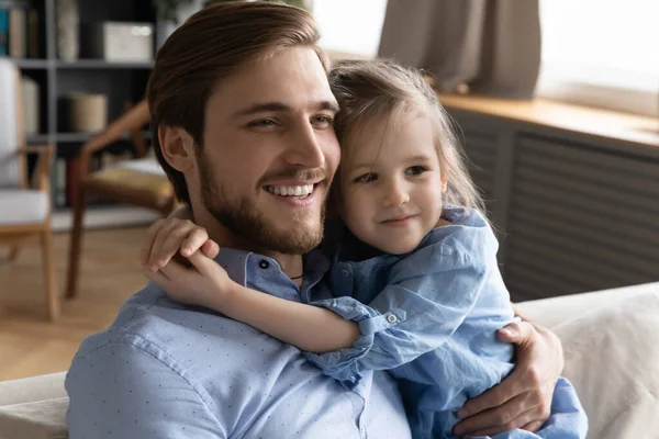 Schattig klein baby meisje knuffelen nek van lachende jonge vader. — Stockfoto