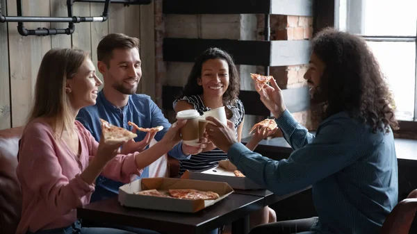 Happy diverse friends eating pizza and having fun in cafe