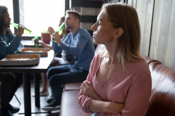 Upprörd ung kvinna sitter förutom olika vänner i caféet — Stockfoto