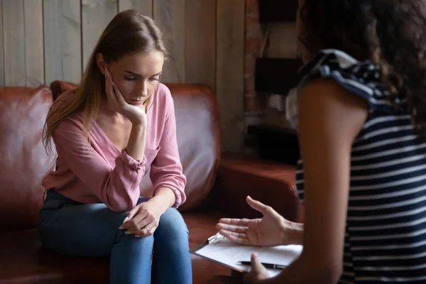 Нещаслива пригнічена молода жінка слухає психолога на зустрічі — стокове фото