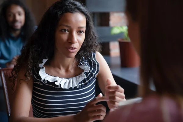 Закройте афроамериканскую женщину, разговаривающую с другом в кафе — стоковое фото