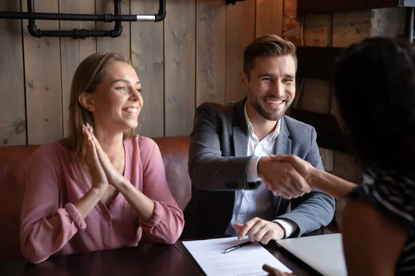 Pareja joven muy alegre haciendo acuerdo de inversión en la reunión — Foto de Stock