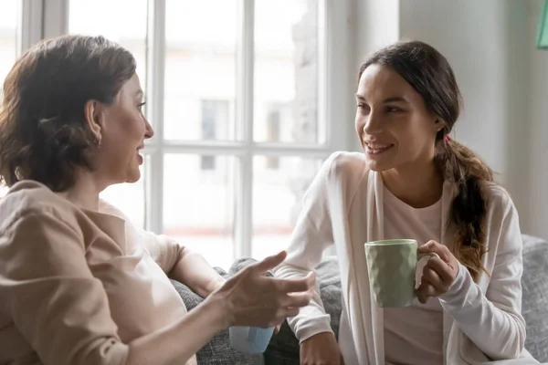 Liefdevolle vijftiger jaren oude vrouw deelt het leven nieuws met volwassen dochter. — Stockfoto