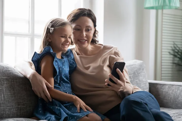 Жінка середнього віку дивиться на екран мобільного телефону з дочкою . — стокове фото