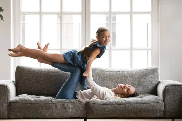 Muda ras babysitter campuran memegang di udara playful gadis kecil. — Stok Foto