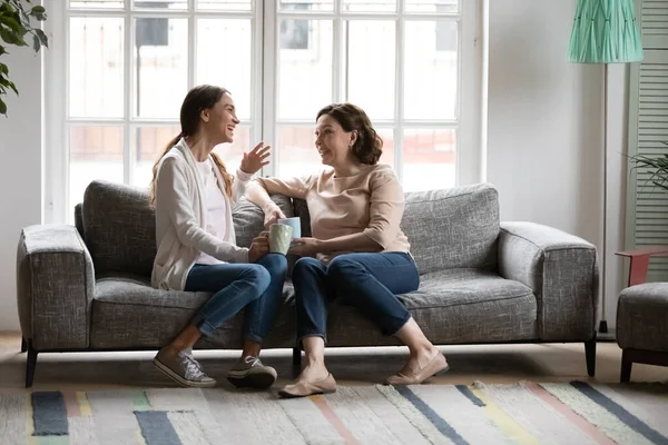 Young mixed race woman drinking coffee with 50s european mother. — Stock Photo, Image