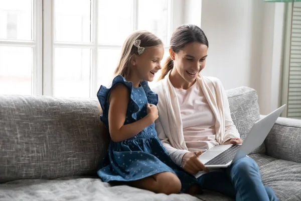 Happy petite fille regarder film drôle sur ordinateur portable avec maman. — Photo