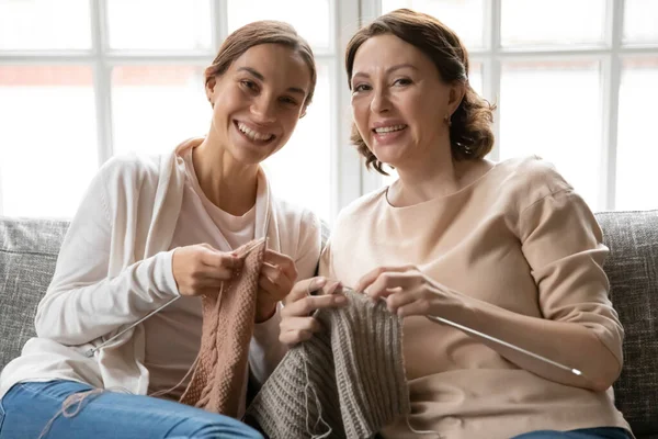 Portrait of smiling young woman knitting stuff with older mum. — Stock Photo, Image
