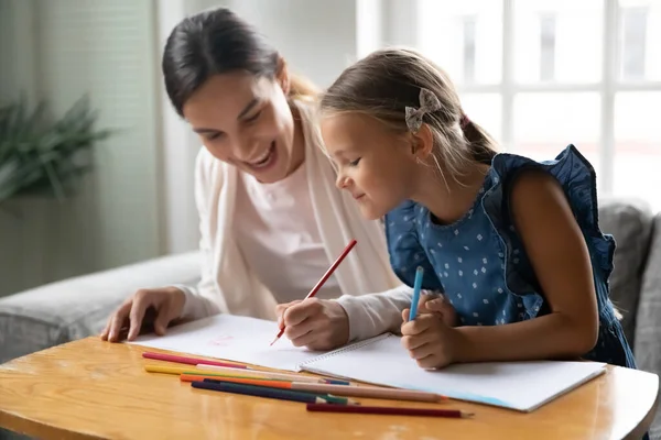 Sonriente madre milenaria disfrutando dibujando con una niña pequeña. — Foto de Stock