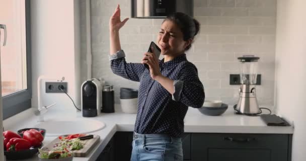 Mujer india cantando usando smartphone como micrófono bailando en la cocina — Vídeos de Stock