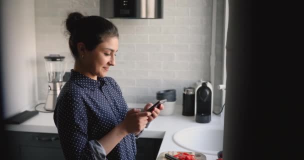 キッチンに立つスマートフォンのカロリーカウンターアプリケーションを使用する女性 — ストック動画