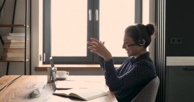 İş kadını kulaklık takıyor. Müşteriyle konuşurken dizüstü bilgisayarı kullanıyor.