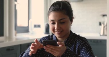 Hintli kadın akıllı telefon tebessümleri kullanır. Sevgilisiyle uzaktan sohbetin tadını çıkar.