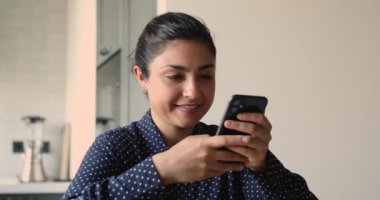 Hintli kadın cep telefonuyla erkek arkadaşının mesajlarına gülüyor.